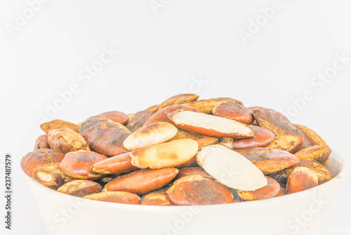 The grilled, roasted of Irvingia malayana, Irvingiaceae, seeds on the white cup with the white bacground. Local seed food in Thailand. photo