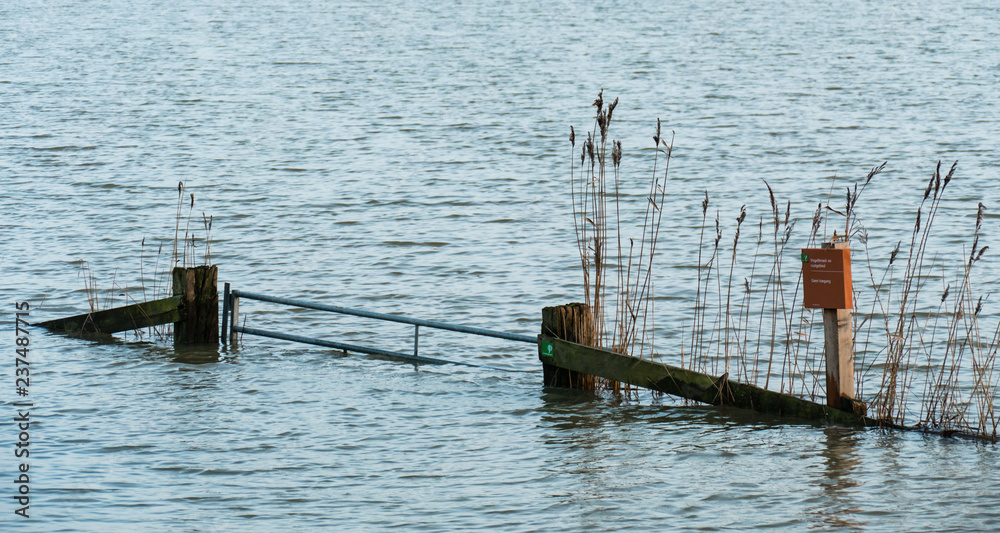 Hardinxveld, Netherlands - 2018-01-14: Gate with reeds and sign in flooded river forelands