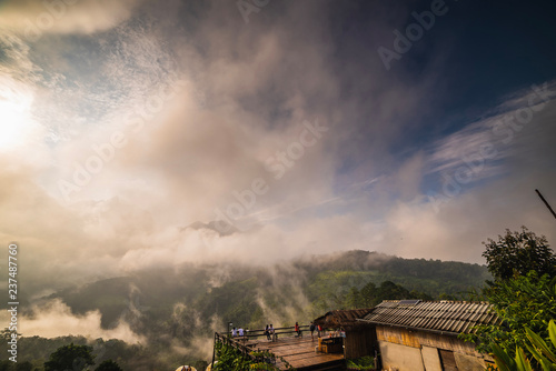 In the morning, Clouds and fog covered densely. People are watching the sunrise on the top of a mountain, which is a beautiful tourist attraction