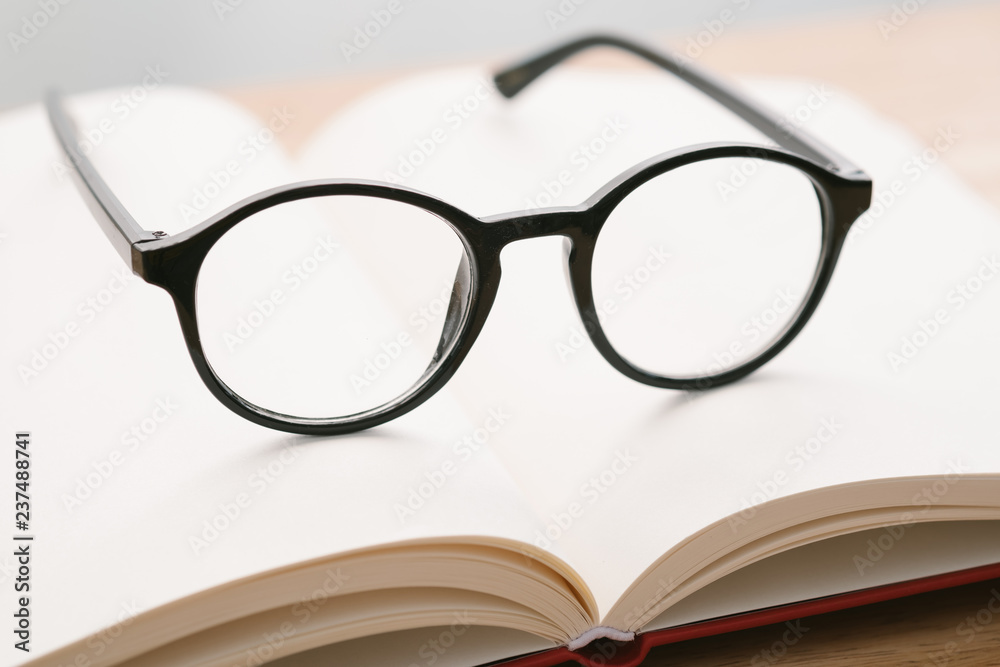 Black glasses on notebook on the table with blurred background. Close-up glasses. Black glasses on notebook on the table with blurred background. Close-up glasses.