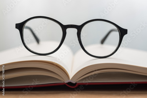 Black glasses on notebook on the table with blurred background. Close-up glasses.