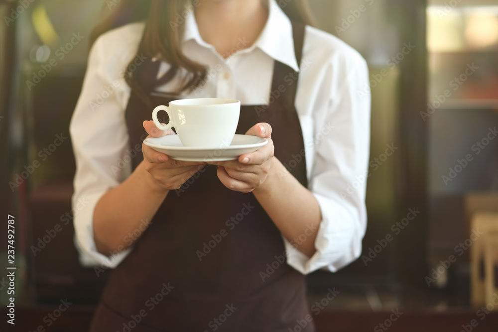 Barista in apron holding coffee in coffee shop Barista in apron holding coffee in coffee shop