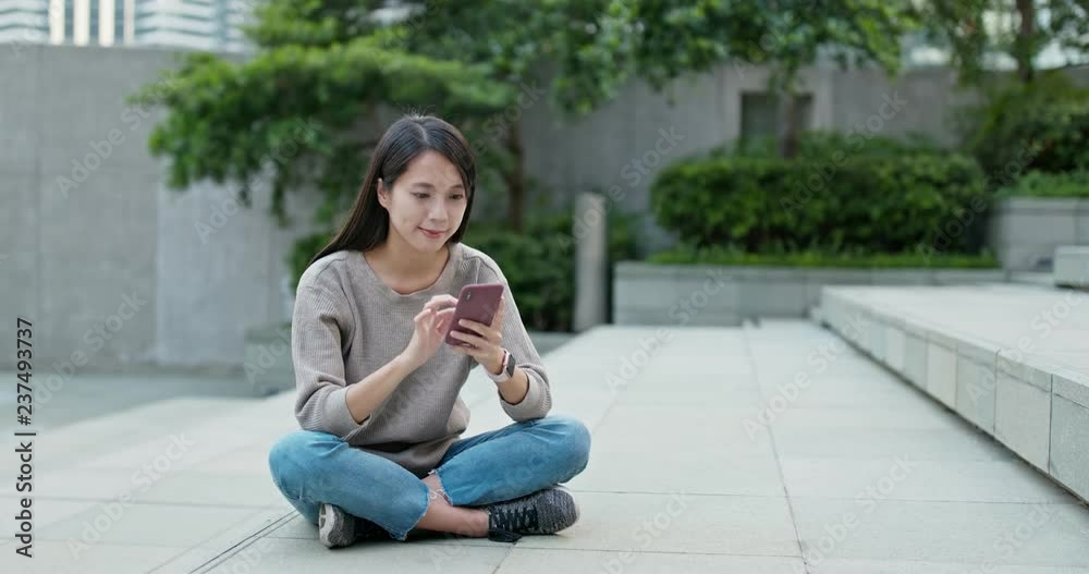 Woman sit on the floor and use of mobile phone in city Woman sit on the floor and use of mobile phone in city