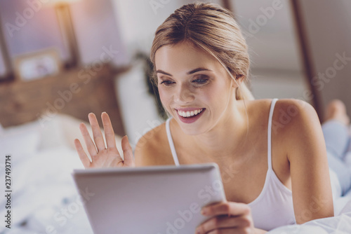 Cheerful young woman making a video call via tablet
