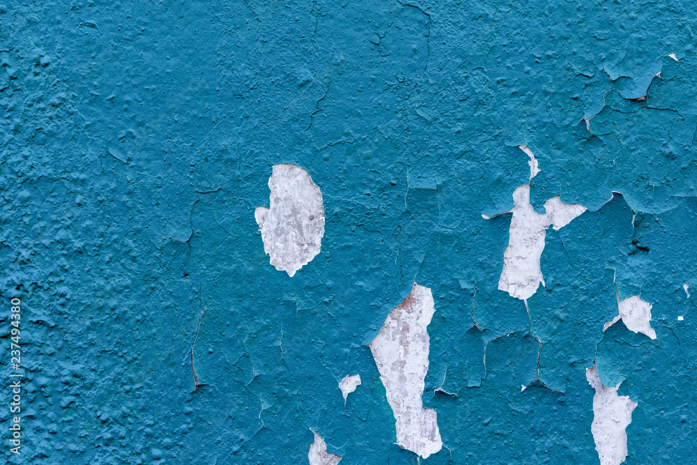 light coloured blue peeling paint on the old rough concrete surface