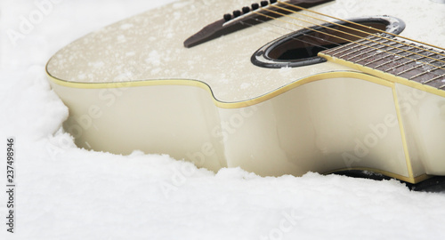 Canvas Print Milk white colour acoustic wooden guitar laying on the whine snow