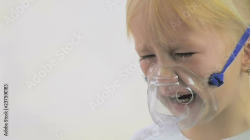 Four-year-old girl doing breathing procedures through an inhaler mask in a hospital in slow motion.