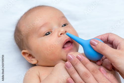 mother cleaning the nose of a newborn with a clyster