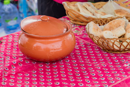 close up of clay bowl and basket with pita on the table  outdoors