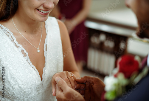 Groom putting on the wedding ring on his bride photo