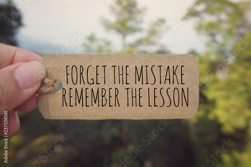 Motivational and inspirational quote - ‘Forget the mistake, remember the lesson’ written on a paper tag. Vintage styled background. photo