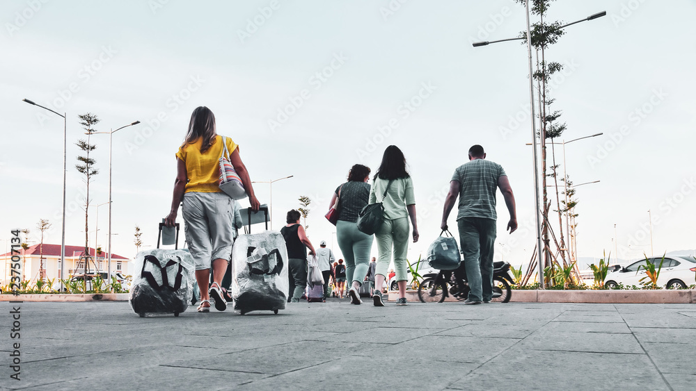 Crowd of tourists with suitcases and bogage. View from the back. Travel as a lifestyle