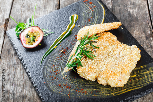 Fried sea fish fillets with rosemary and sesame on stone slate background close up. Healthy food. Top view