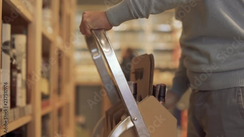 Wallpaper Mural Man hands close up put wine bottles on the shelfs Man is using ladder to reach higher Torontodigital.ca