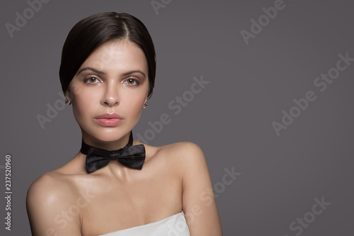 Fashionable female portrait. Nude shoulders. Natural makeup. Gray background