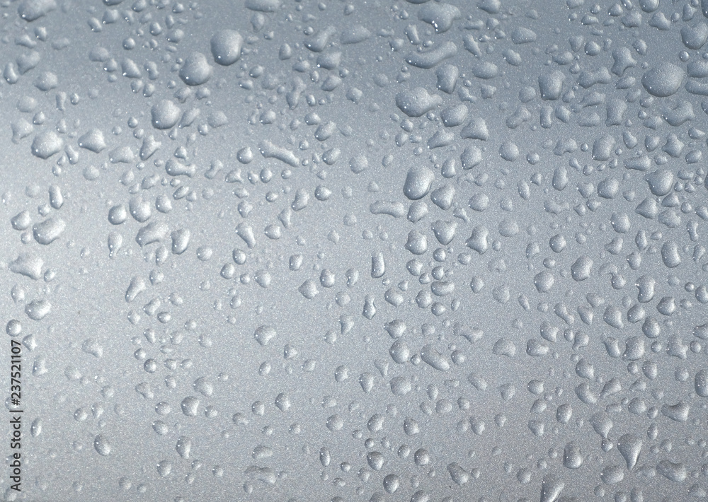 Dew droplets  twinkle on car's rar window. Condensation on the outside of a sillvercar in early cold morning hours.