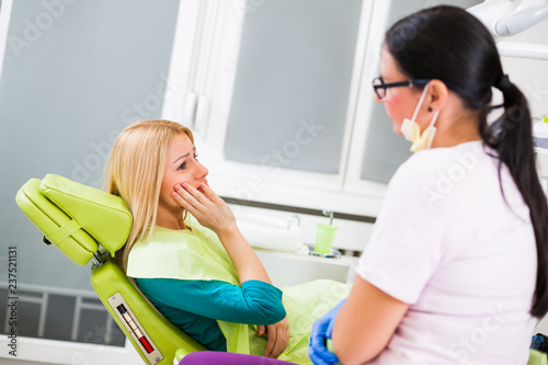 Young woman at dentist. She has toothache.