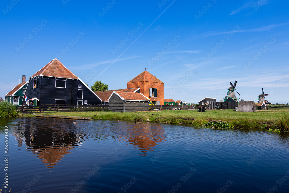 Reflections in the water of the farms and windmills on a lovely day, with a blue sky. Zaanse Schans. Holland