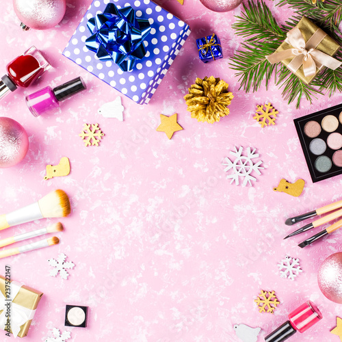 Make up cosmetics, presents and Christmas decorations on artistic pink background, copy space
