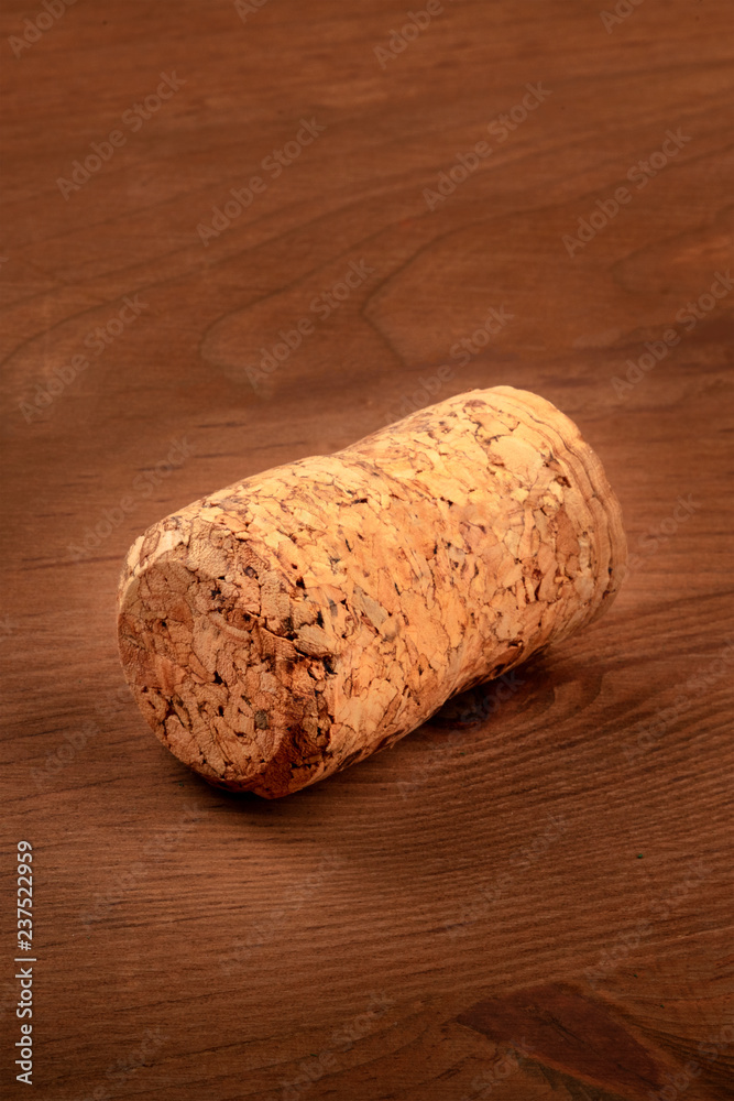 A closeup photo of a champagne cork on a dark rustic wooden background with copy space