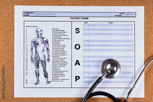 Patient SOAP note sheet, stethoscope on corkwood background. Flat lay.