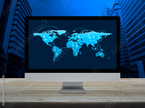 Connection line with global world map on desktop computer monitor screen on wooden table over modern city tower and skyscraper, Communication online concept, Elements of this image furnished by NASA