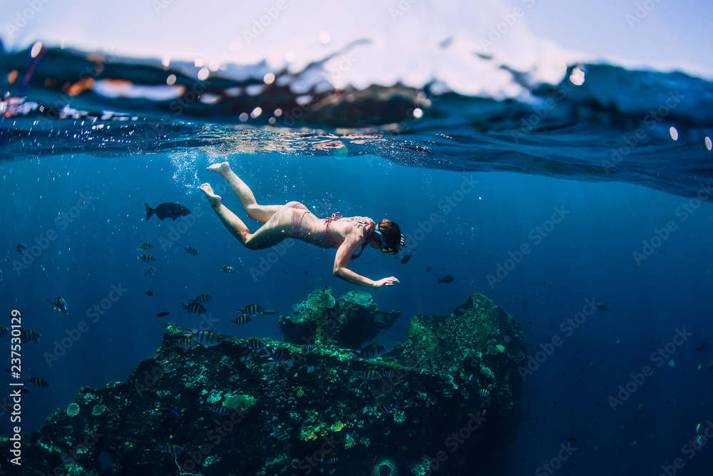 Woman free diver dive in the tropical ocean at shipwreck