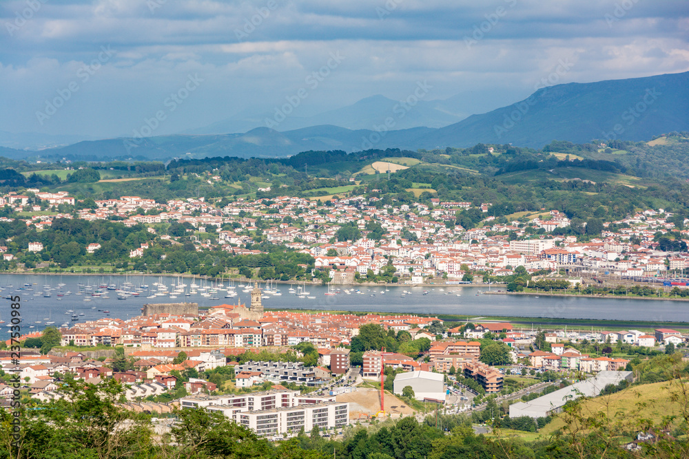Distant view of typicall fishermen village of Hondarribia, and Henday in the Basque Country, Spain. With some small fishing boats on the foreground and the medieval tower bell on the background