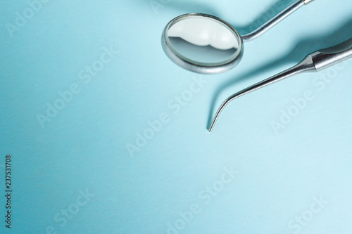 Dental mirror and explorer on blue light background with copy space, close up.