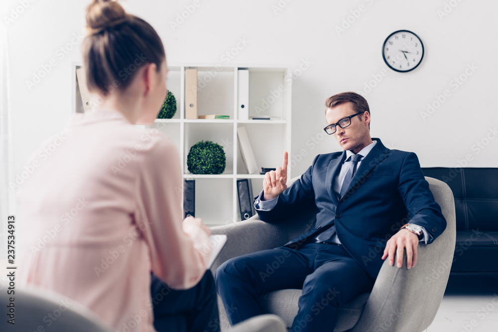 Obraz premium handsome businessman showing one finger up while giving interview to journalist in office