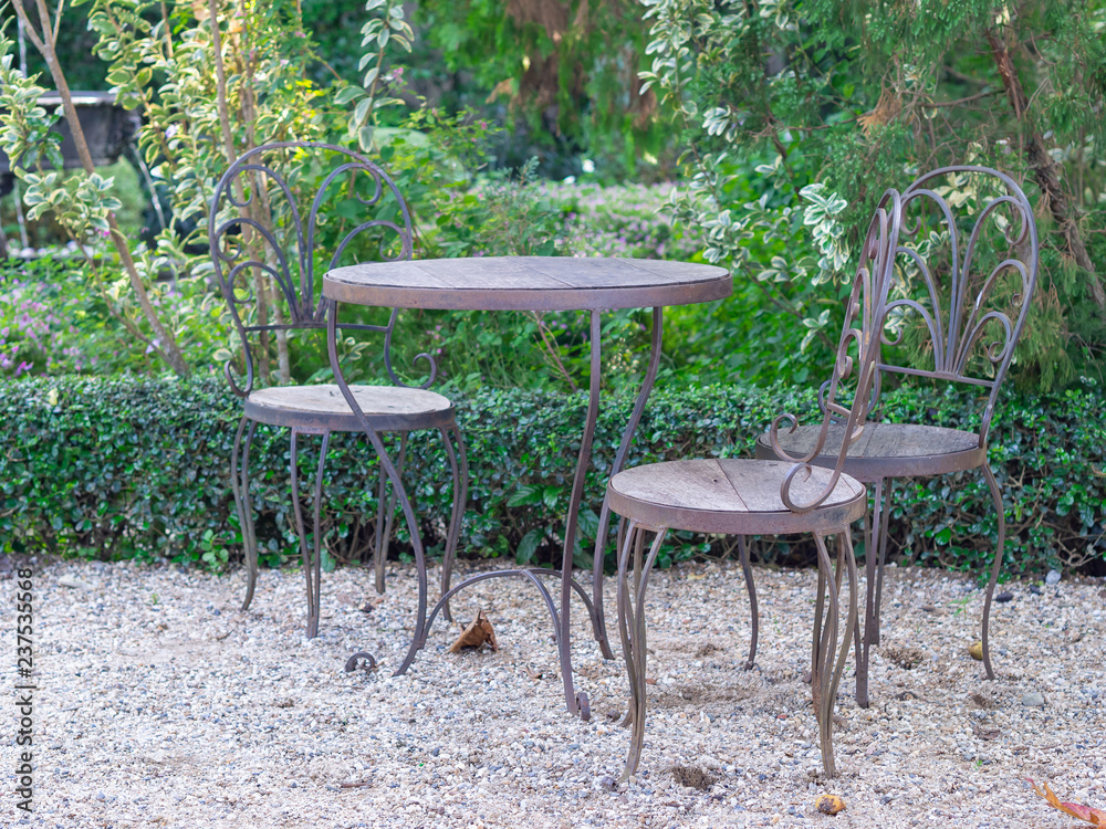 Steel chairs and table with wooden seat in the garden.