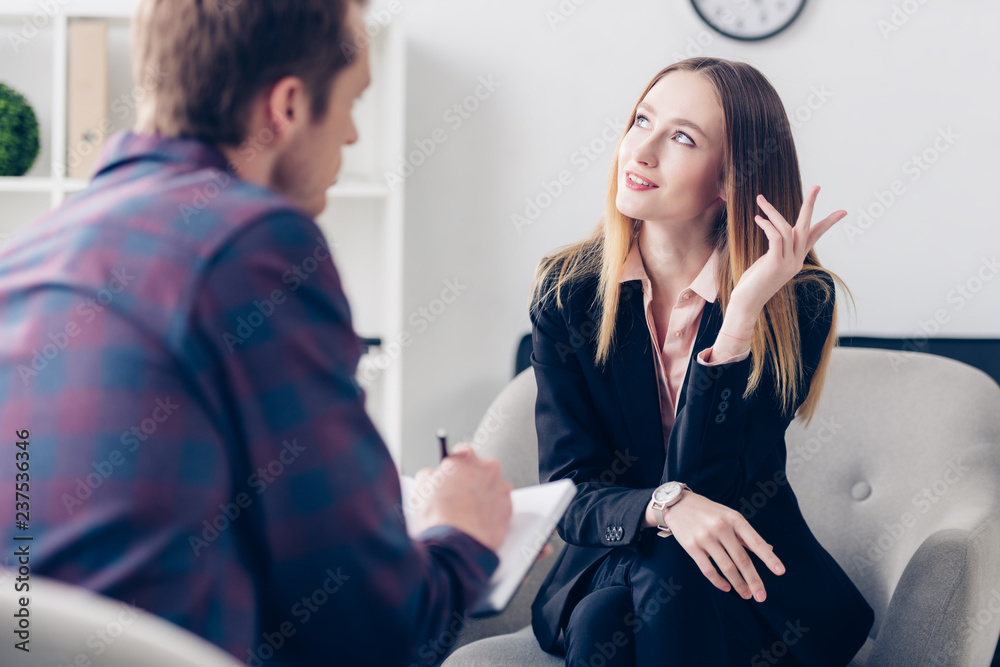 businesswoman in suit giving interview to journalist, gesturing and looking up in office businesswoman in suit giving interview to journalist, gesturing and looking up in office