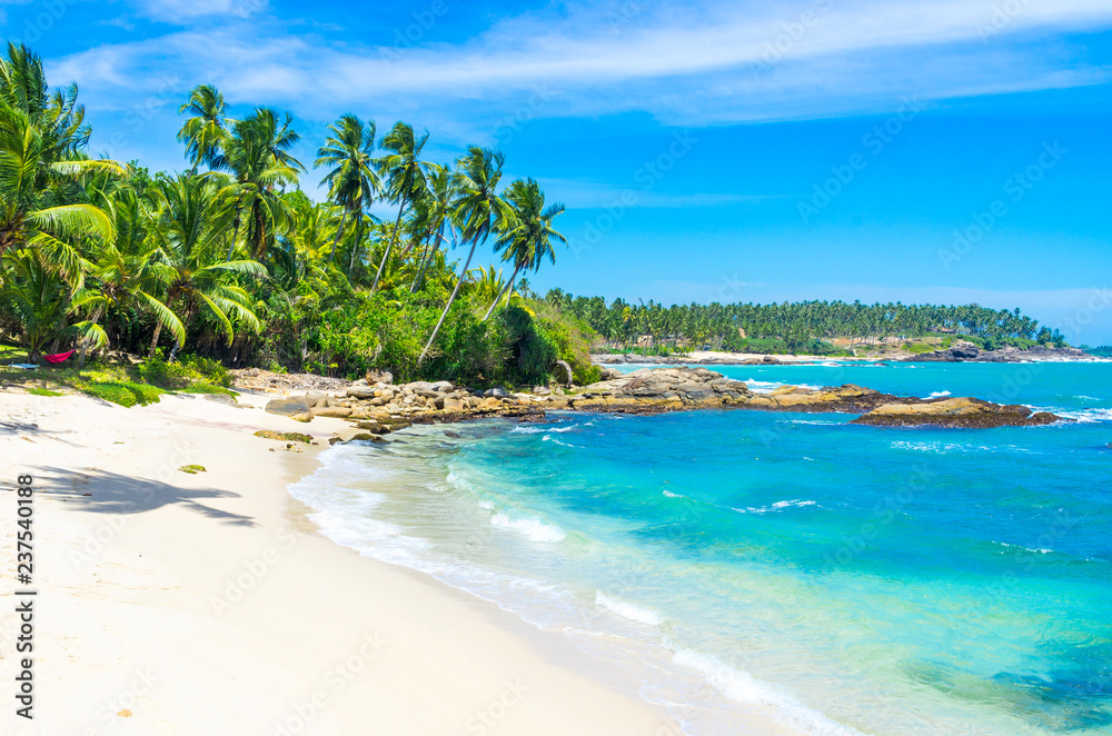 Tropical beach on a Sri Lanka's coast, coconut palms, white sand and the azure ocean. Beautiful tropical landscape Tropical beach on a Sri Lanka's coast, coconut palms, white sand and the azure ocean. Beautiful tropical landscape