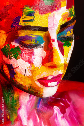 face of young girl painted with colorful makeup and body art