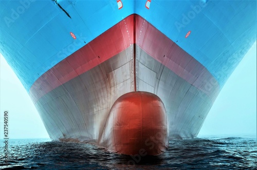 Front view of a large cargo ship with bulbous bow sailing through calm ocean, maritime transport and global logistics concept. © Mariusz