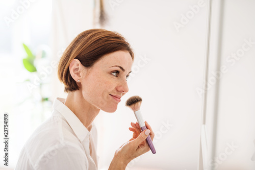 A young woman putting on a make-up in the morning in a bathroom.