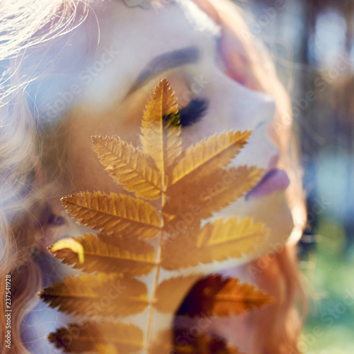 Portrait of a woman with a double exposure  the girl and the blurred nature of the photo is not in focus. The leaves on the woman s face