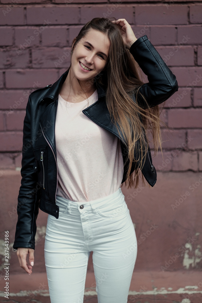 Young beautiful caucasian girl posing in a black leather jacket on a brick wall background. Young beautiful caucasian girl posing in a black leather jacket on a brick wall background.
