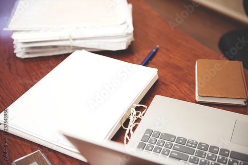 Pile of unfinished documents on office desk  Stack of business paper. A file folders  with documents and important documents. Laptop  pen  notepad. Workplace. 