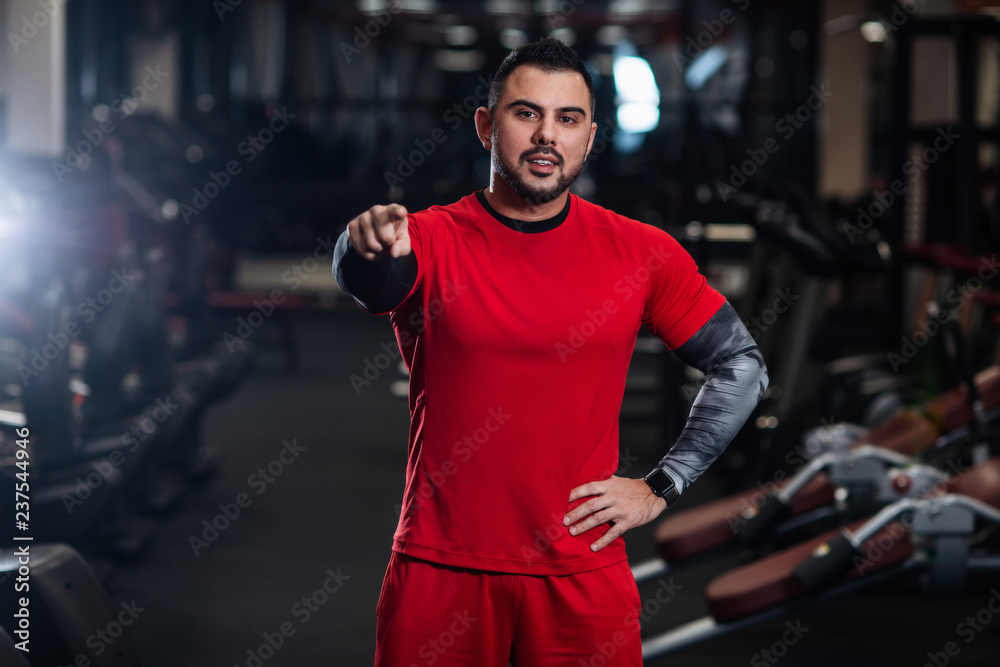 Handsome man with big muscles, posing at the camera in the gym Handsome man with big muscles, posing at the camera in the gym