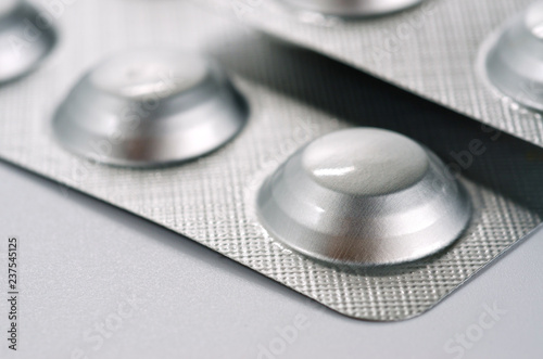 Plate with round medical pills silver color close-up shot