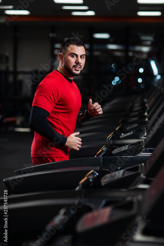 Man in sportswear running on treadmill at gym in red clothes © Vladimir