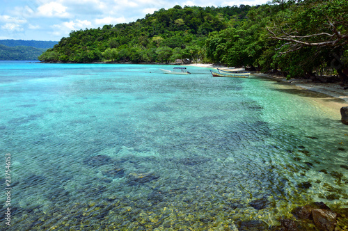 Remote and tranquil beach in Pulau Weh, Indonesia. Crystal clear water and lush green water front.