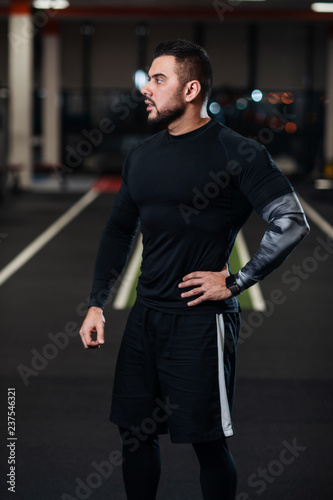 Handsome man with big muscles, posing at the camera in the gym © Vladimir