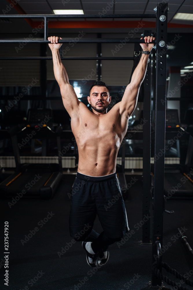 Athletic man making pull-up exercises on a crossbar in the gym Athletic man making pull-up exercises on a crossbar in the gym