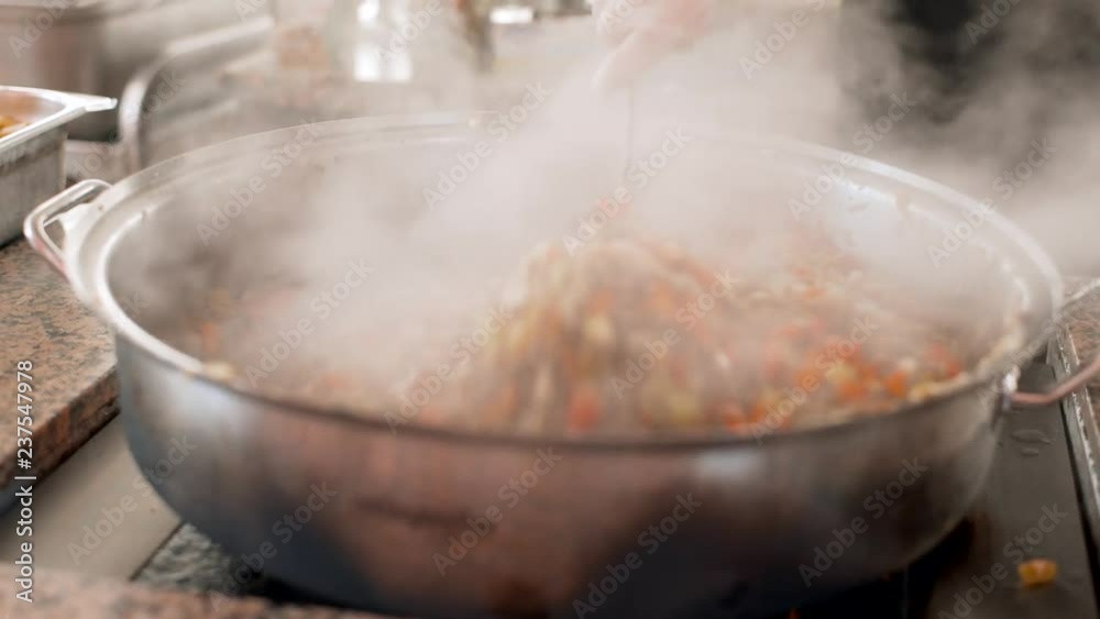 Cooking pilaf in a cauldron. Asian traditional dish - pilaf. National tasty food. Close up. Steamed food. Street food festival. Rice with meat and vegetables. 4k Cooking pilaf in a cauldron. Asian traditional dish - pilaf. National tasty food. Close up. Steamed food. Street food festival. Rice with meat and vegetables. 4k