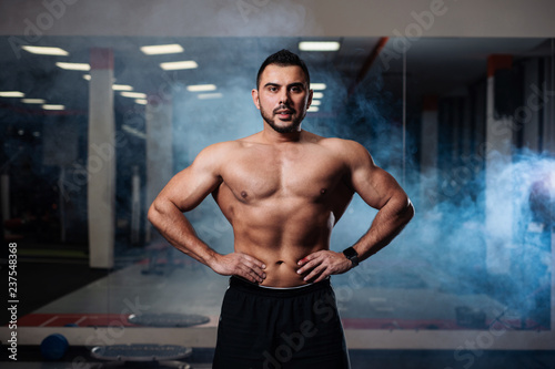 Athletic man posing, showing off his muscles in the gym