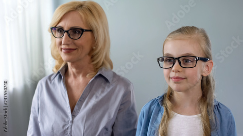 Aged woman and her little granddaughter visiting eyes specialist, health care