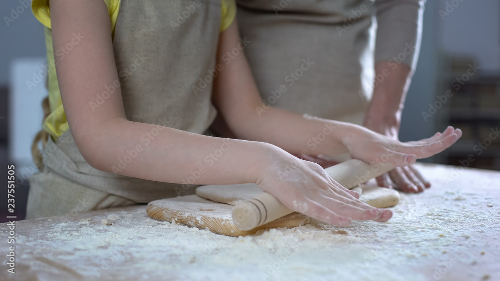 Hands of grandmother and granddaughter pouring flour on plank, cooking time