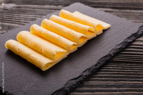 Piece and slices of cheese on a wooden background